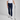 Person wearing navy golf pants and white shoes, holding a golf club on a gray background
