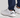 White golf shoes with black Under Armour logo worn with navy pants on a light gray background