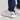 White golf shoes with black Under Armour logo worn with navy pants on a light gray background