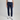 Person wearing navy pants and white sneakers on a gray background