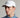 A man wearing a golf cap in white, featuring a ball marker and tonal logo