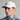 A man wearing a golf cap in white, featuring a ball marker and tonal logo