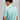 Man wearing a light blue polo shirt with a brand logo on the back against a gray background
