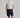Man wearing a light gray polo shirt and navy shorts on a gray background