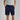 Person wearing navy shorts and a light gray shirt on a plain background