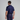 Man wearing a navy blue polo shirt and pants with white shoes on a gray background