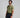 Man in green polo shirt and black pants holding a golf club on a gray background