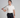 Man in off white polo shirt and black pants holding a golf club on a gray background