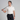 Man in off white polo shirt and black pants holding a golf club on a gray background
